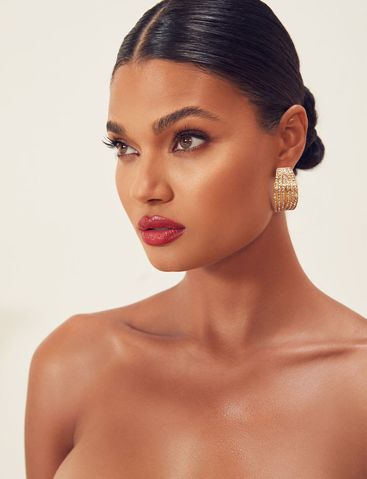 A model's hair is pulled back into a sleek low bun exposing a full face holiday makeup. SHOP HOLIDAY GLAM