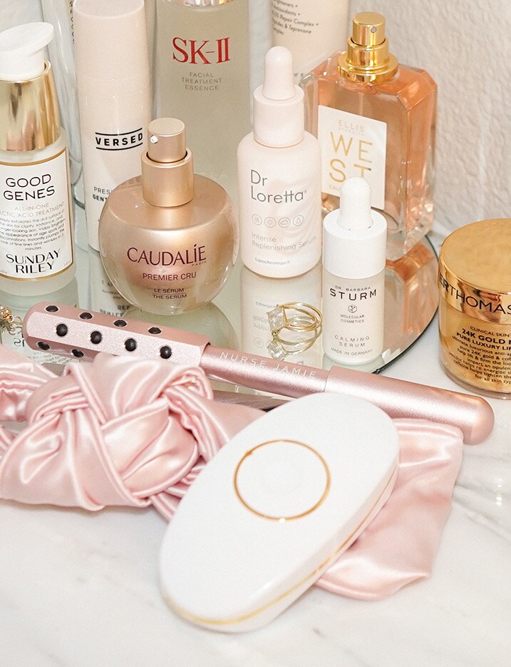 A variety of skincare tools, serums and oils are displayed on a mirror and marble surface. Shop Skincare Tools.