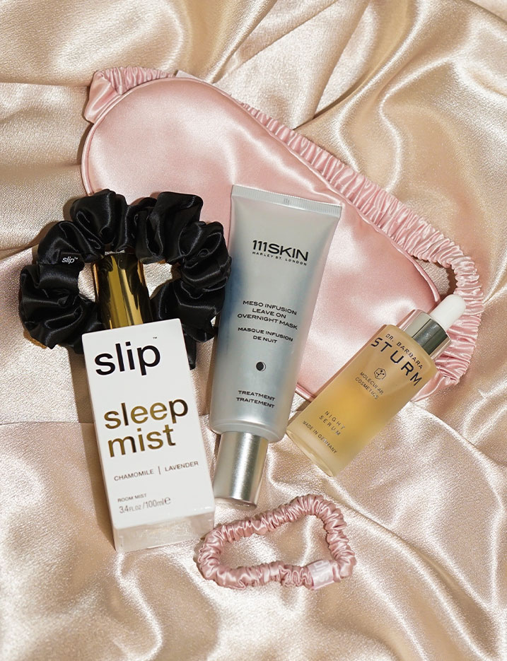Nighttime beauty and sleep essentials arranged on a silk sheet. Shop Sweet Dreams.