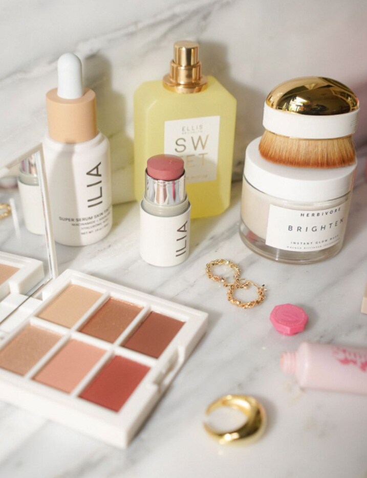 A variety of skincare and makeup products featuring clean beauty brands are scattered on a marble countertop. Shop Clean Beauty.