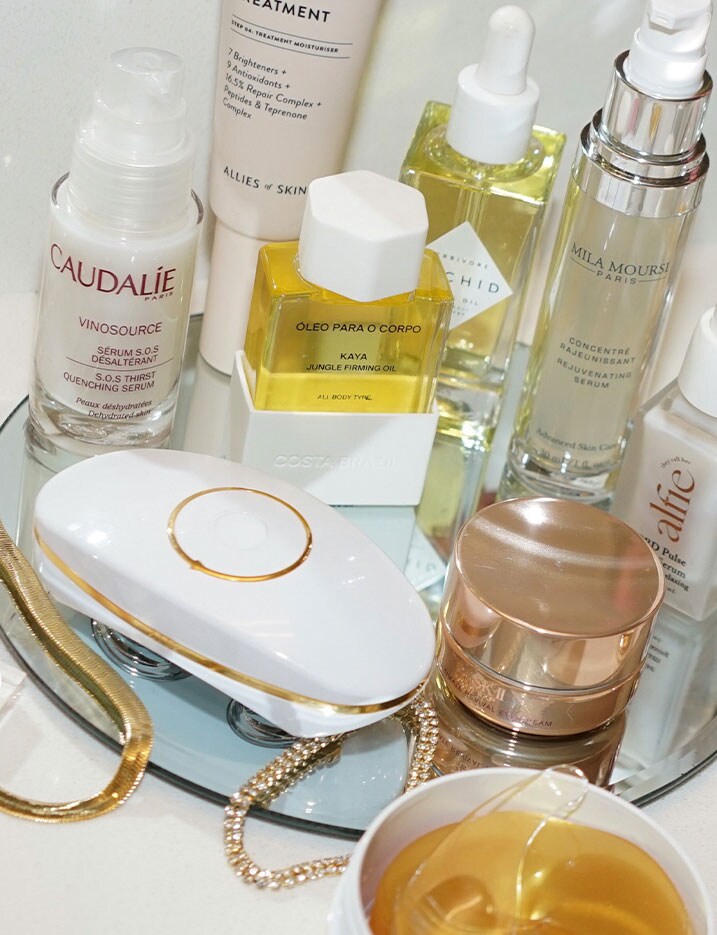 A variety of skincare products and a Ziip device sit on top of a glass plate vanity. Shop Skincare Tools.