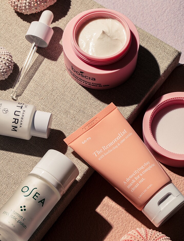 A variety of skincare products sit on linen surface.