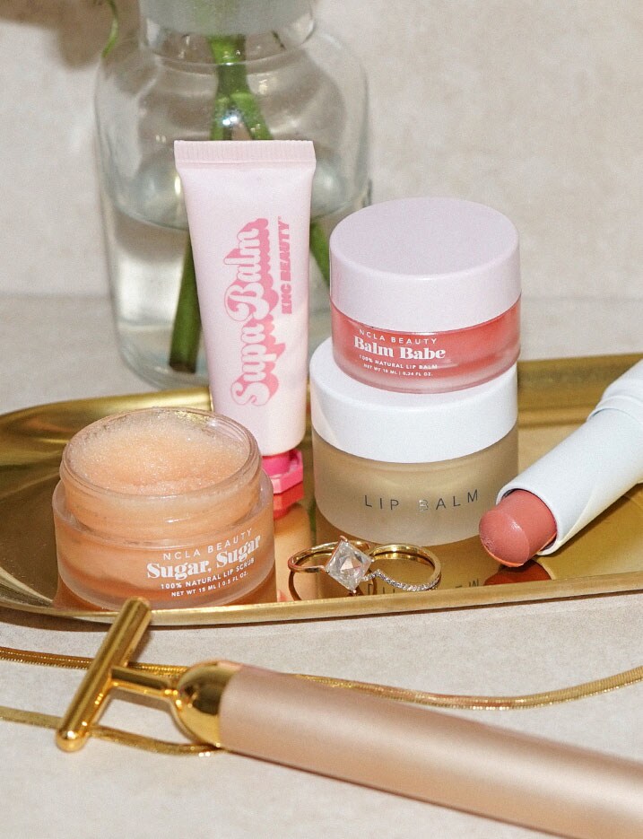 Various lip products scattered on a golden metal tray. Shop Protect Your Pout.