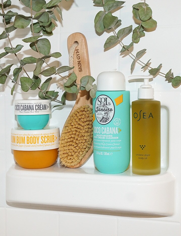 Various bath products sit on a bathtub shelf.Shop Bath & Body.