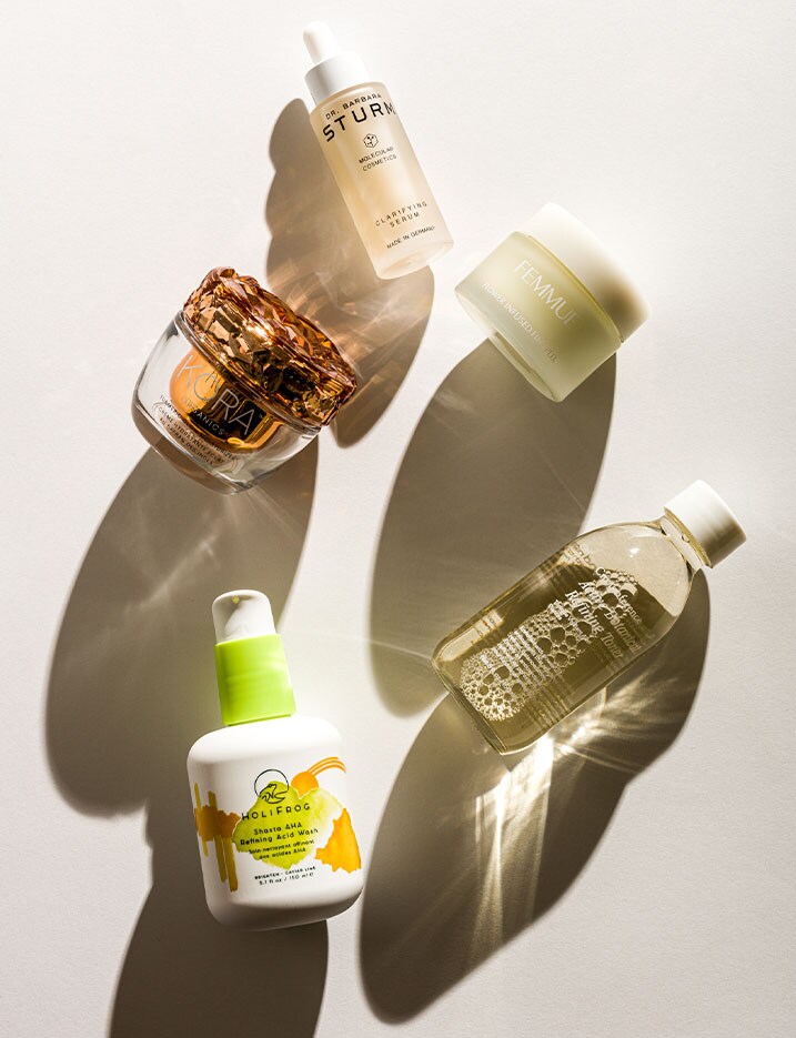 Variety of skincare products displayed on their side casting long shadows across a white table.