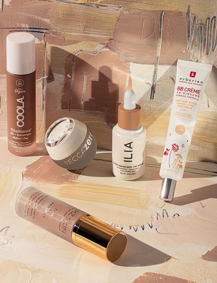 Brown and cream tone packaged BB Cream products sit on cream paper with various brush strokes of different shades of brown.