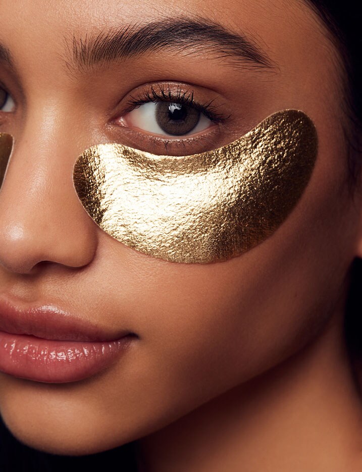 Model wearing gold eye mask under her left eye.