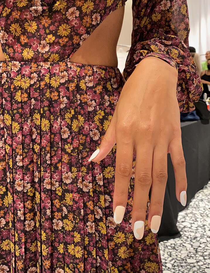 Model's hands with white and nude color manicured nails.