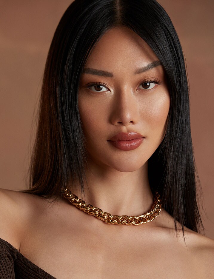 Model with defined dark brows, warm glowing skin and cheeks, and warm berry lipstick.