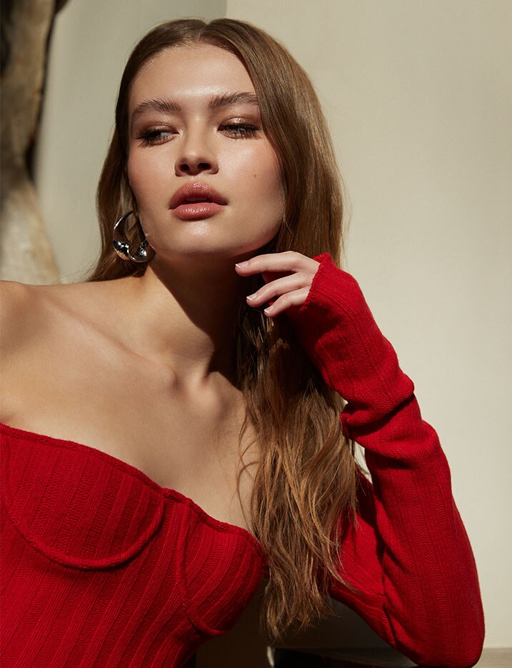 A close up of a model in a red knitted long sleeve top