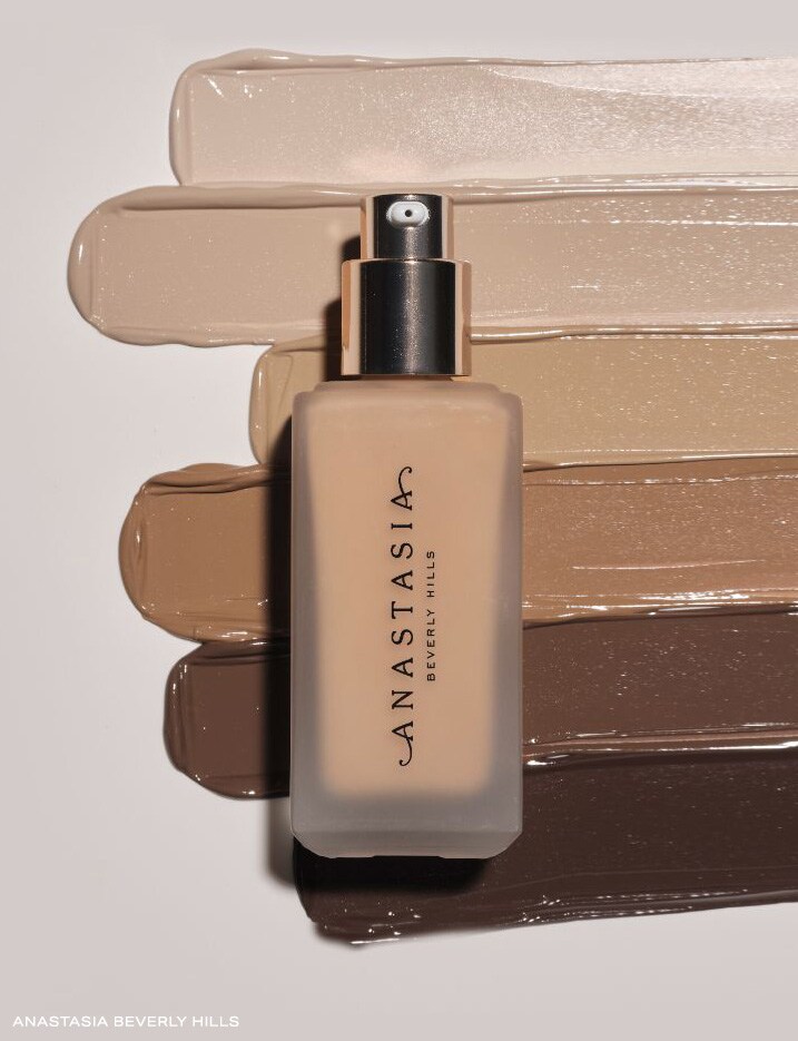 Bottle of Anastasia Beverly Hills Impeccable Blurring Second-Skin Matte Foundation on top of a variety of shades.