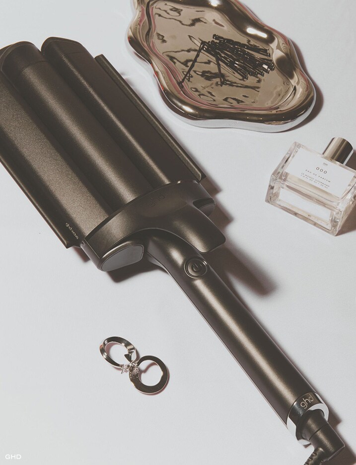 Hair styling tool neatly placed with hair beauty products and a pair of earrings.
