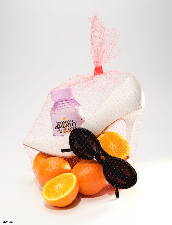 Lemme immunity gummies packed in a product bad with a heel, sunglasses, and oranges.