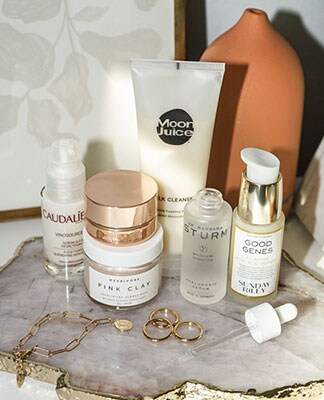 A model sitting next to a fireplace wearing a silver sequined mini dress with long sleeves. Looks We Love: Low-Key Luxe. Shop the Edit.