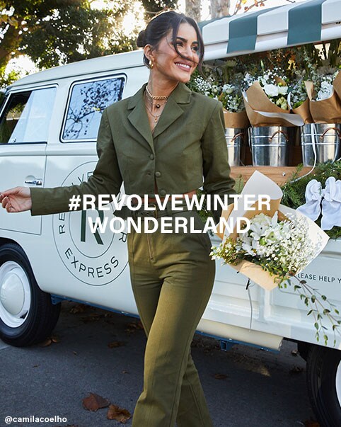 Tatiana Elizabeth Price standing in front of a REVOLVE Express truck wearing a brown cable knit turtleneck sweater and a denim skirt. Camila Coelho standing in front of a REVOLVE Express truck holding a bouquet of flowers and wearing a green cropped blazer and matching belted pants. Nicole Williams English standing in front of a REVOLVE Express truck wearing a black and white houndstooth printed coat, a black crop top, and belted, black faux leather pants. Vale Genta standing in front of a REVOLVE Winter Express truck filled with wreaths and holding a bouquet of flowers wearing a grey rib knit sweater and matching lounge pants and white booties. Ayla Woodruff standing in front of a REVOLVE Winter Express truck wearing black overalls and a white off the shoulder ruffle top. #REVOLVEwinter Wonderland. Shop the Edit.
