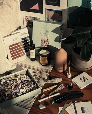 A display of puzzles, pictures, oil diffusers and a plant. Home Sweet Home. Shop Now.