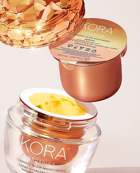 A close-up photo of KORA Organics Turmeric Glow Moisturizer and refillable pod. New! KORA Organics Turmeric Glow Moisturizer. Shop KORA Organics.