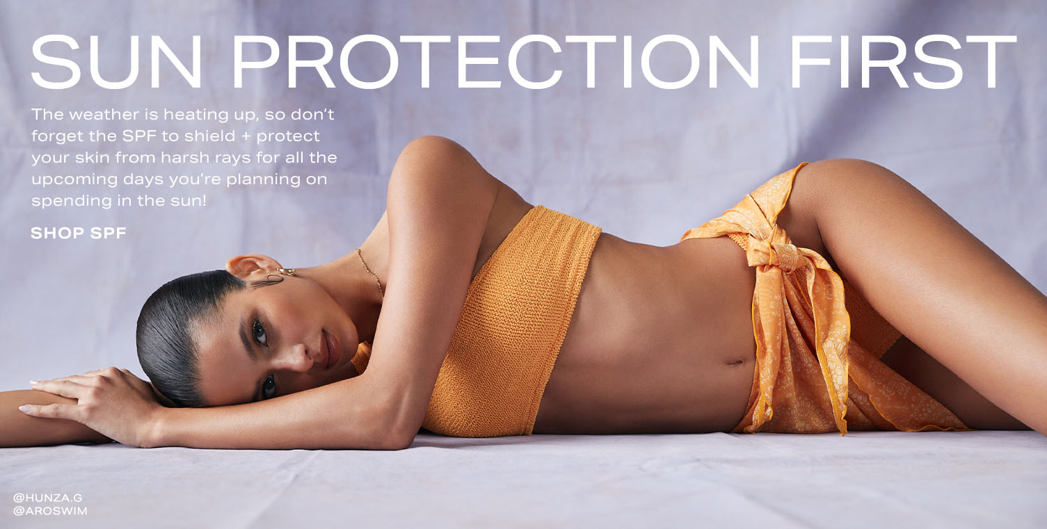Model laying on her side in an orange bikini. Reads: Sun Protection First. The weather is heating up, so don’t forget the SPF to shield + protect your skin from harsh rays for all the upcoming days you’re planning on spending in the sun! Shop SPF