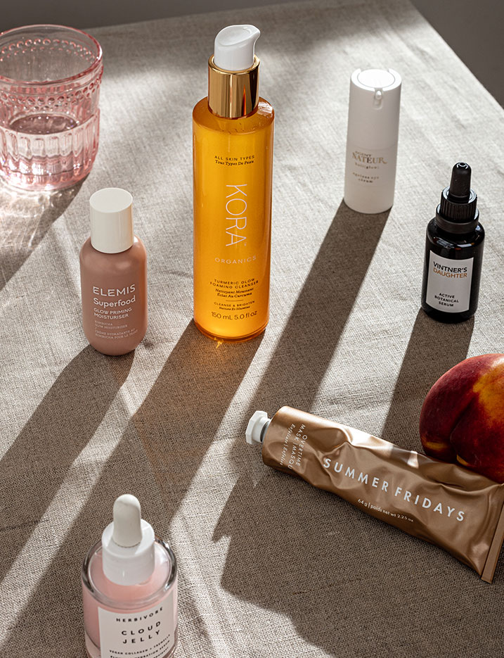 A variety of skincare products on dark linen cloth.