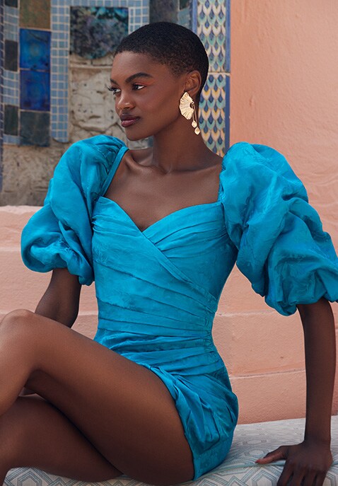 Model wearing a vivid blue exaggerated puffy sleeved dress with a heart-shaped neckline, further dre