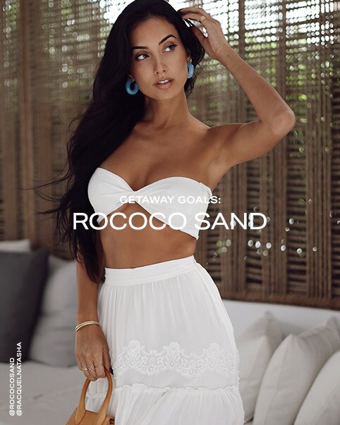 Racquel Natasha wearing a white bandeau top and white skirt. Getaway Goals: ROCOCO SAND. Shop ROCOCO SAND.