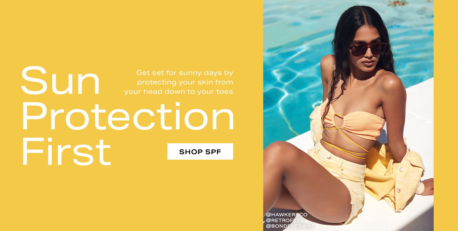 Model lounging by the pool in a bright yellow two-piece swim suit. Reads: Sun Protection First. Get set for sunny days by protecting your skin from your head down to your toes. Shop SPF.