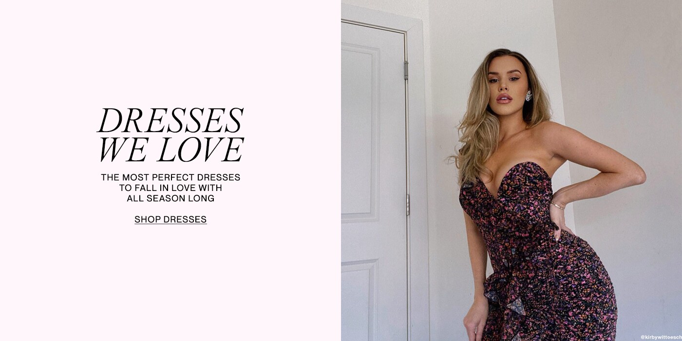 Woman wearing a black and pink floral strapless dress posing in front of a white wall. Dresses We Love. The most perfect dresses to fall in love with all season long. Shop Dresses.