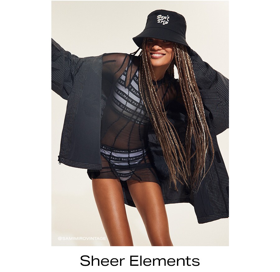 Model in black sheer mini dress layered over matching sports-style intimates, topped with an oversize jacket.