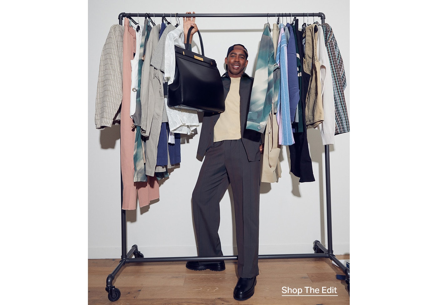 Jason Bolden posing under a clothes rack filled with essential pieces picked by Jason Bolden.