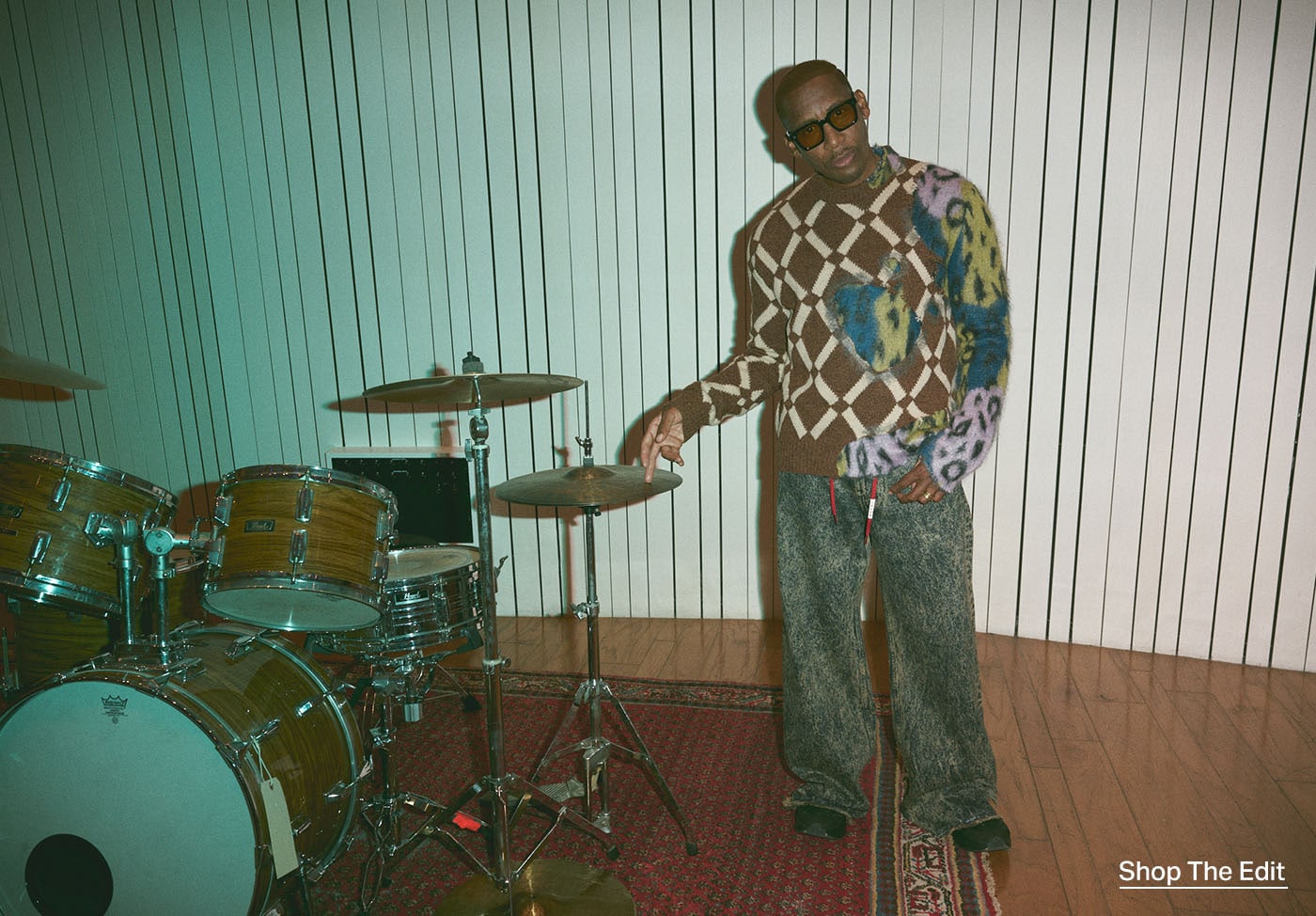 Raphael Saadiq standing next to a drum set.