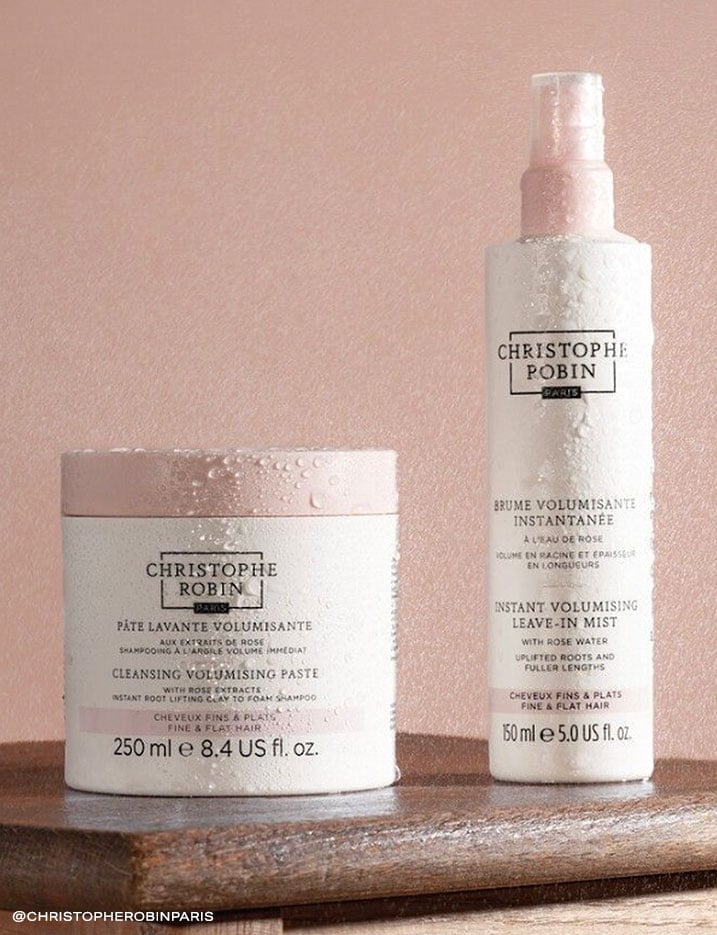 A container of Christopher Robin cleansing volumizing paste next to a bottle of volumizing leave-in mist.