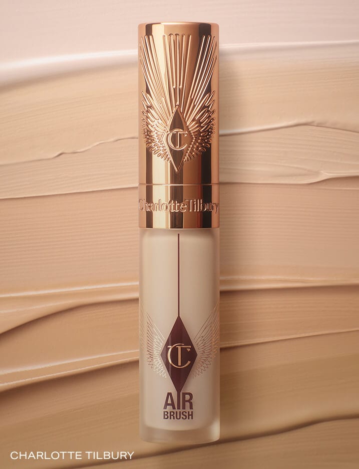 Charlotte Tilbury Airbrush Flawless Blur Concealer in front of smears of various different shades.