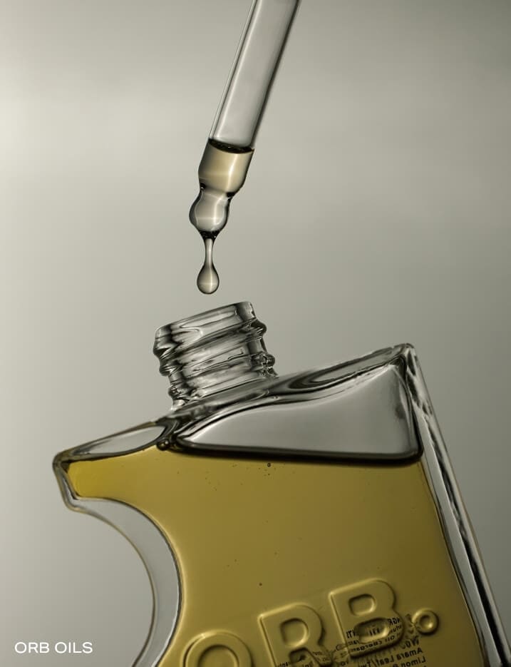 An open bottle of Orb Oils fragrance oil driping into the bottle.