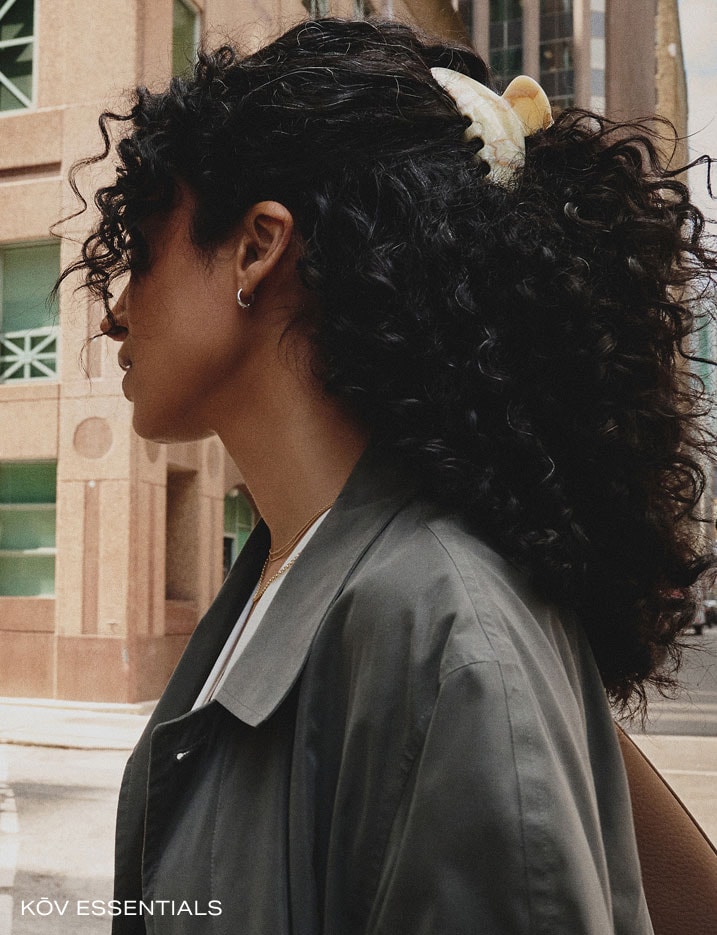 Model with curly long black hair held up with a hair clip.