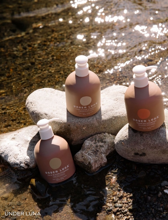Variety of Under Luna bottles on river rocks.