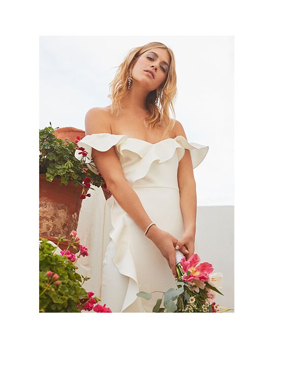 Model holding flowers and wearing white dress